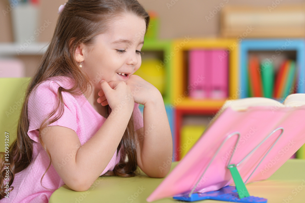 Girl is sitting at the table and reading a book Girl is sitting at the table and reading a book