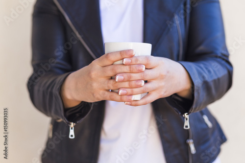 close up of woman hands holding a cup of coffee. sunny weather. white background. outdoors. Lifestyle.