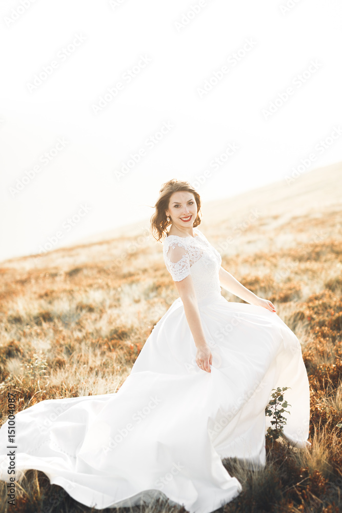 Beautiful bride with a bouquet on mountain background at sunset