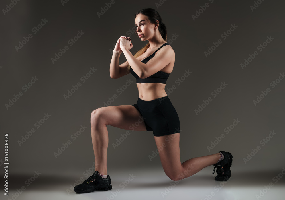 Strong sportswoman make sports exercises over grey background