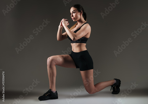 Strong sportswoman make sports exercises over grey background