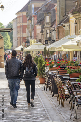 A young couple walks hand in hand in Republicii Street in the historic center of Brasov, Romania photo