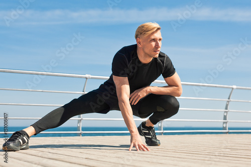 Confident man stretching on pier