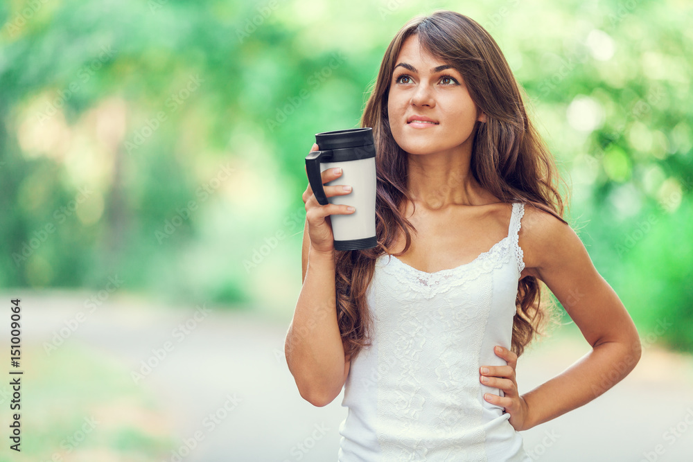 Brunette girl with cup of coffee in the park.