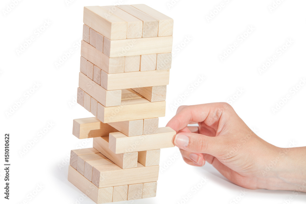 The tower from wooden blocks and man's hand take one block The tower from wooden blocks and man's hand take one block