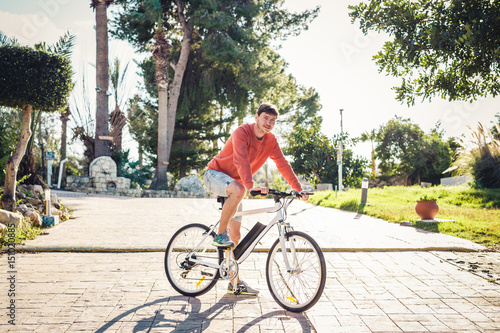 Portrait of handsome guy riding bicycle in the park