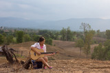 Old girl playing the old guitar on the backdrop is an area for farming, the forest disappears