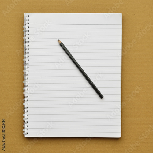 Notebook with pencil on cardboard background. 