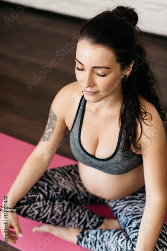 Pregnant young woman doing breathing and relaxation exercises. Young woman expecting a baby doing yoga.