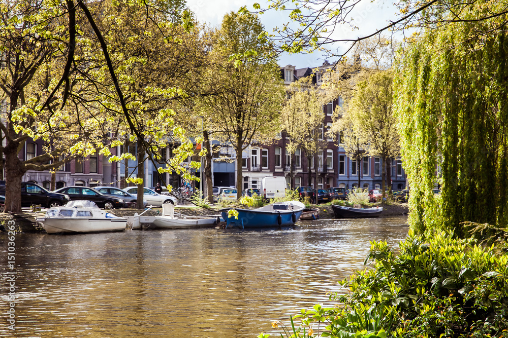 Amsterdam canal view with small boats. Spring day in the city Amsterdam canal view with small boats. Spring day in the city