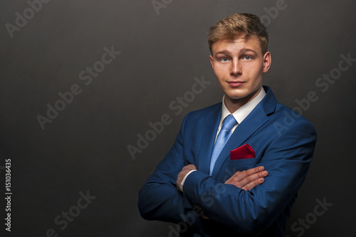Young handsome man in blue suit smiling on dark background © Wisiel