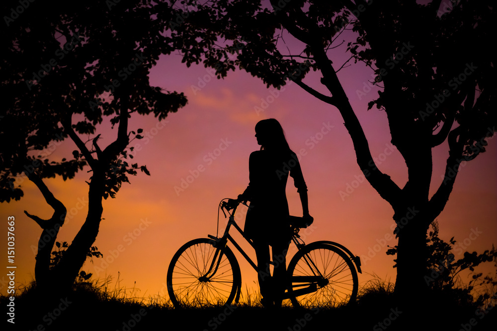 Obraz premium A young woman is standing with bicycle, resting, with the night sky background