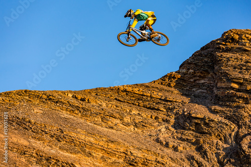 A man is jumping on the bicycle, on the background of blue sky . Sunny autumn day.