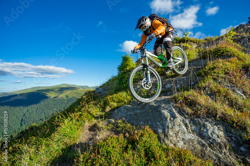 A man is riding bicycle, on the background of mountains and blue sky. Beautiful summer day.