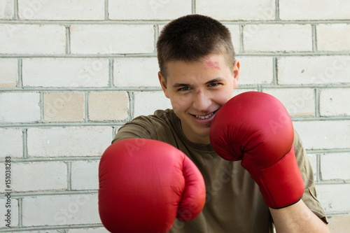 17 year old teenager boy with a battered face and boxing gloves. Boxing. Sport. 