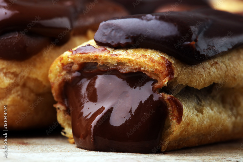 Traditional French dessert. Eclair with chocolate icing. Wooden background Traditional French dessert. Eclair with chocolate icing. Wooden background