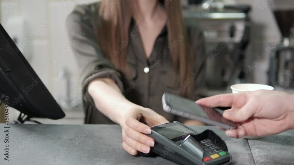 Paying with smartphone. Handsome man making payment transaction with his mobile phone to waiter in modern cafe Paying with smartphone. Handsome man making payment transaction with his mobile phone to waiter in modern cafe
