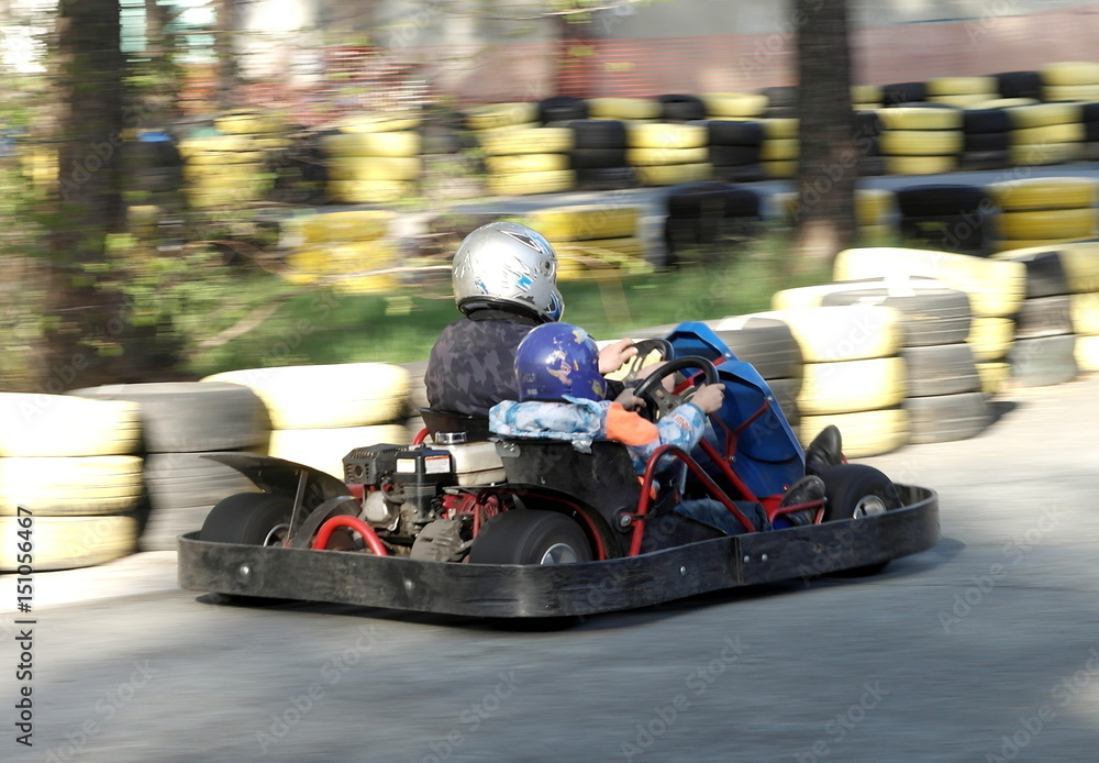 Father and son are riding in a karting park.