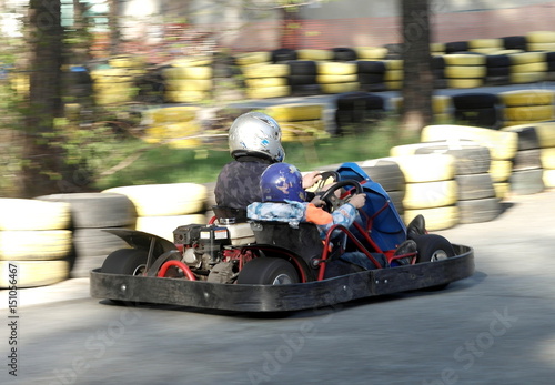 Father and son are riding in a karting park.