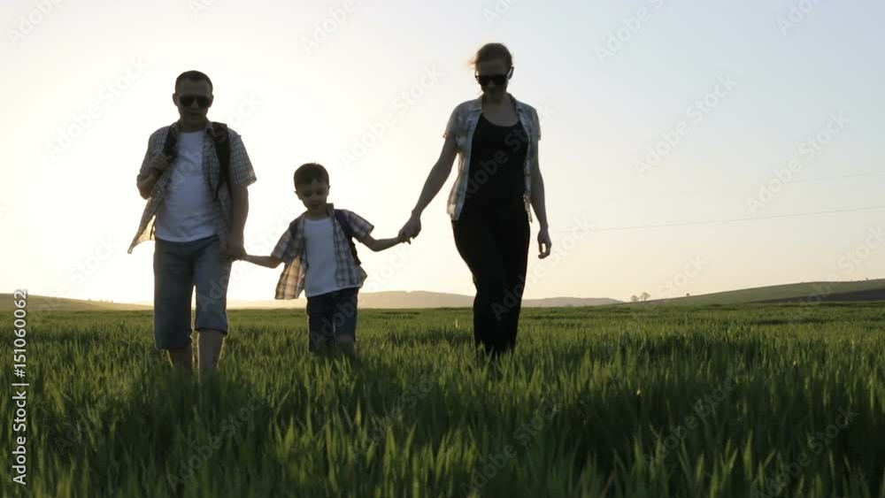 Father, mother and son walking on the field at the day time. People having fun outdoors. Concept of friendly family. Father, mother and son walking on the field at the day time. People having fun outdoors. Concept of friendly family.