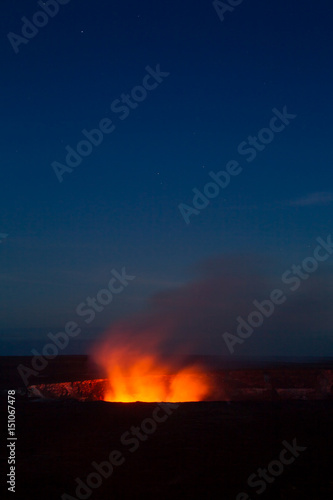Ein Lavasee im Halemaumau Krater auf dem Kilauea beleuchtet aufsteigende vulkanische Dämpfe vor dem Nachthimmel im Hawaii Volcanoes National Park auf Big Island, Hawaii, USA.
