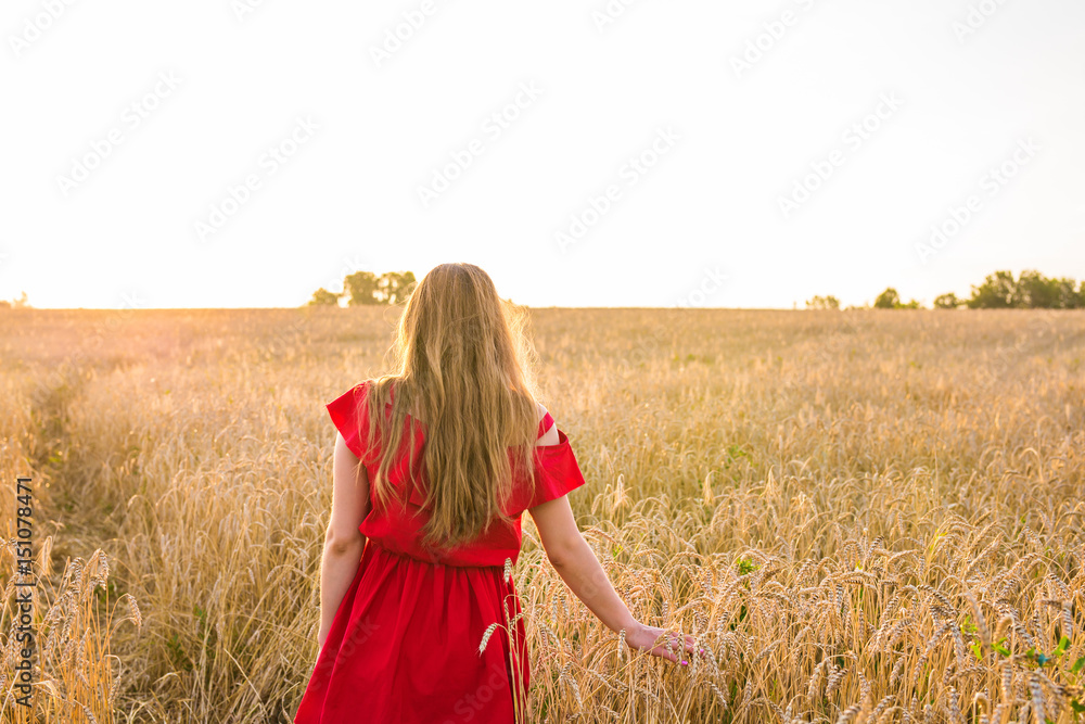 Obraz premium happiness, nature, summer, autumn, vacation and people concept - young woman in the field from back