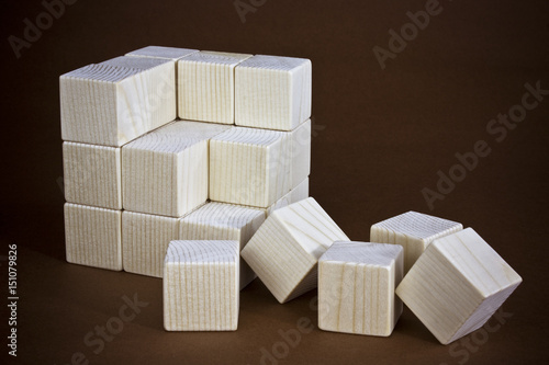 Broken cube mades with wooden bricks. Still -life picture taken in studio on brown background. photo