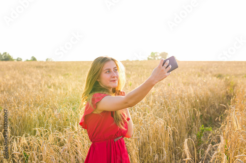 Portrait of a smiling young girl making selfie photo in the field