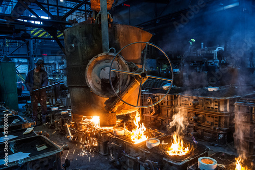 Foundry worker pouring hot metal into cast. Molten metal. Left over material from the steel manufacturing process is poured away on at a Steel Foundry