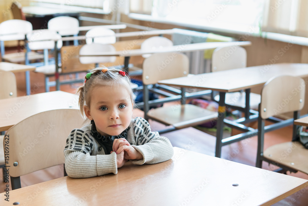 Portrait of a beautiful girl sitting at a school desk in an empty classroom Portrait of a beautiful girl sitting at a school desk in an empty classroom