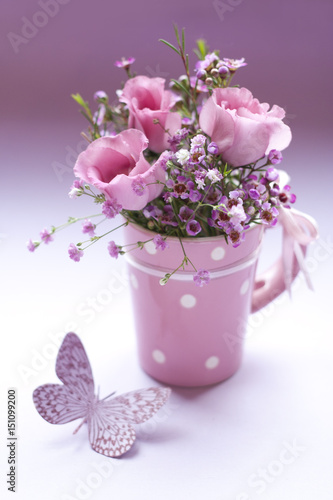 Lisianthus mit Wachsblumen und Schleierkraut in einer Tasse mit Schmetterling photo