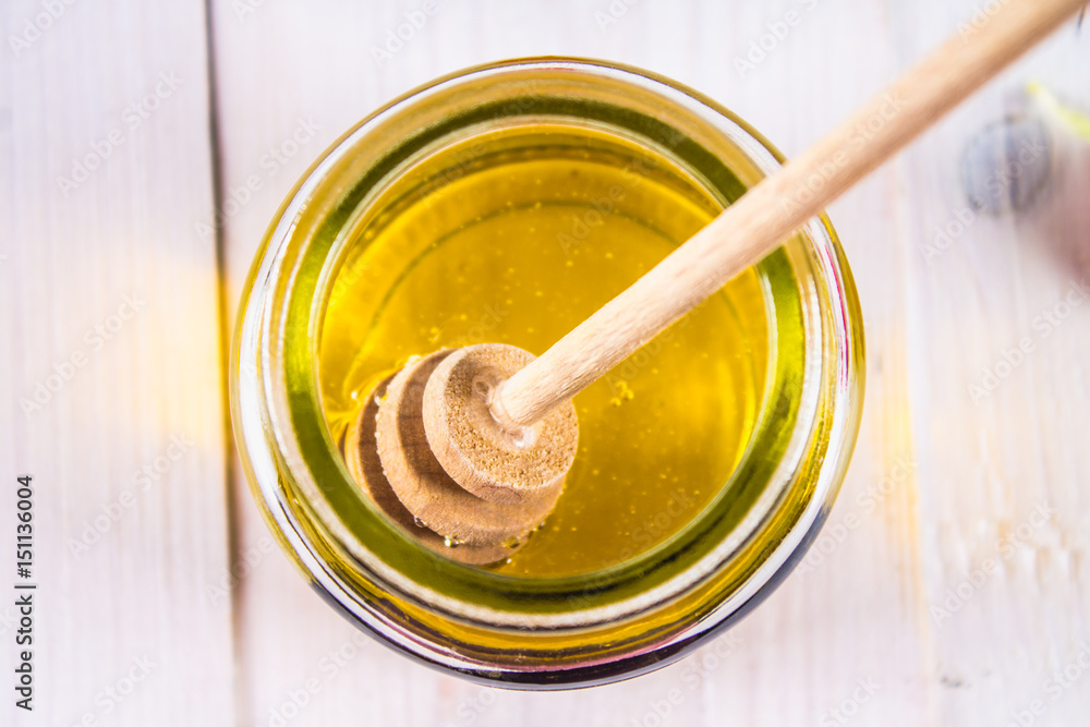Honey can with spoon, on white table. View from above.