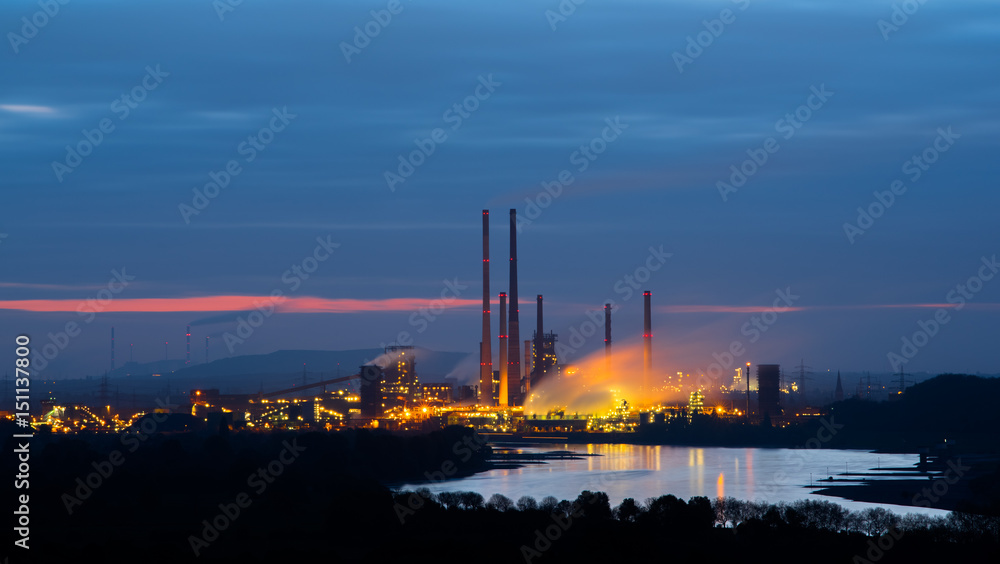 Industry or power plant during early sunrise with steam or smoke rising Industry or power plant during early sunrise with steam or smoke rising