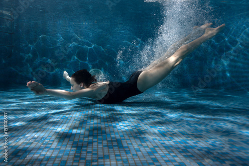 Woman quickly swims under the water, her body in air bubbles.
