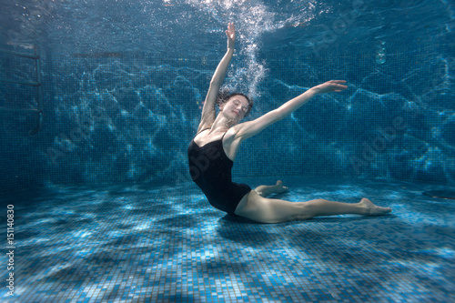 Woman shows beautiful postures under the water in the pool.