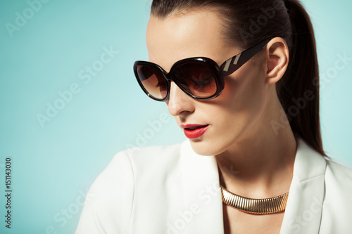 Fashion beauty portrait of female wearing sunglasses and red lipstick. 