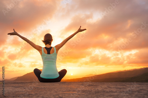 Its a new day concept. Young woman feeling happy and free looking a the beautiful sunrise.  photo