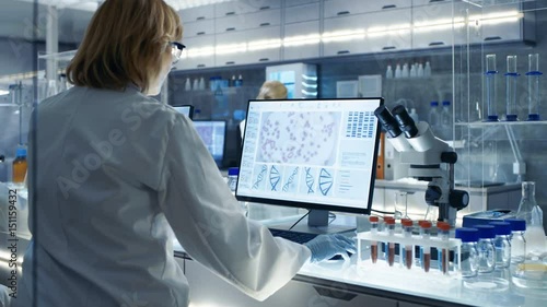  Senior Female Scientist Works with High Tech Equipment in a Modern Laboratory. Her Colleagues are Working Beside Her.Shot on RED EPIC-W 8K Helium Cinema Camera.