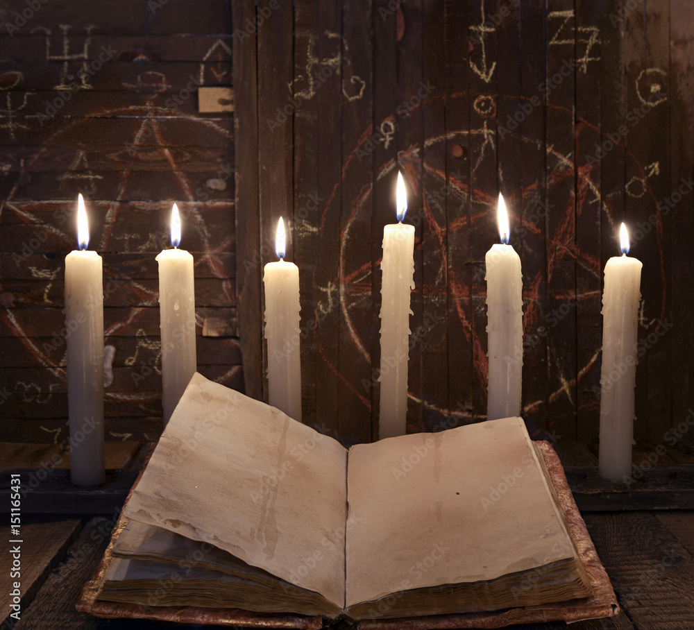 Black magic ritual with burning candles and open book against wooden  background. Stock Photo | Adobe Stock