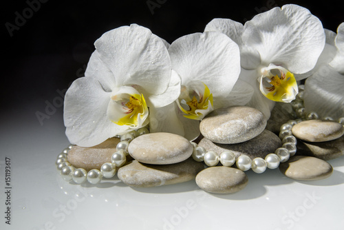 flat stones on a white glass on the background of white orchids
