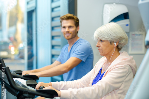 young man and elderly lady using exercise machines