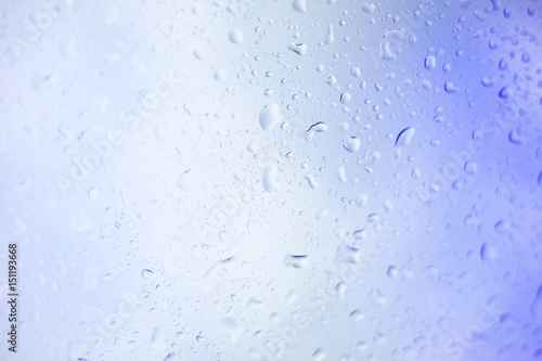 Water drops on glass, rain drop background defocused on blue surface.