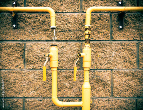 Yellow gas pipe on a stone. brick wall. The gas pipe does not hold gas..