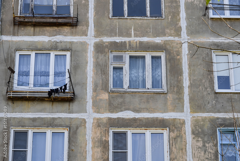 A multi-storey residential building of the Soviet period. Gray faceless windows and walls. Russia. A multi-storey residential building of the Soviet period. Gray faceless windows and walls. Russia.