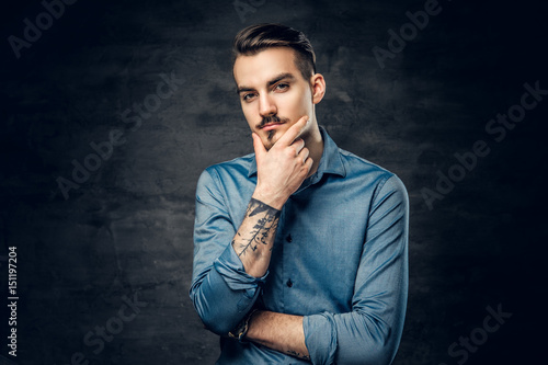 Thoughtful male with tattooed arm.