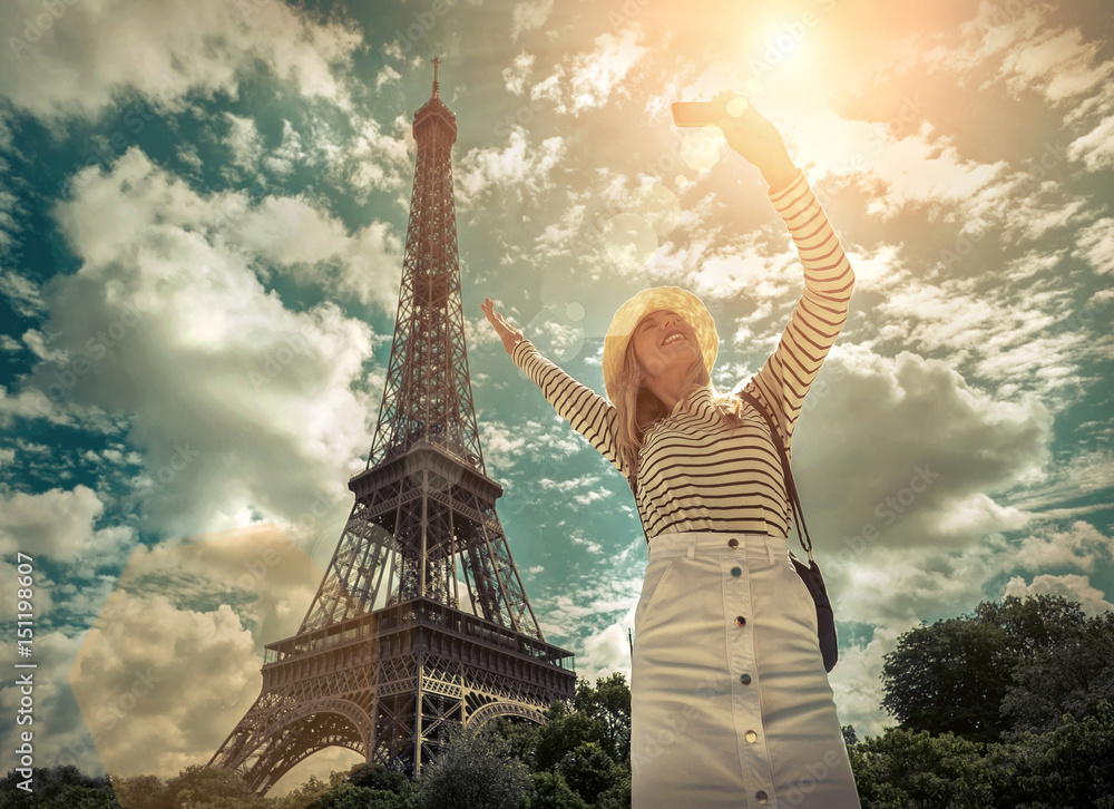 Fototapeta premium Woman tourist selfie near the Eiffel tower in Paris under sunlig