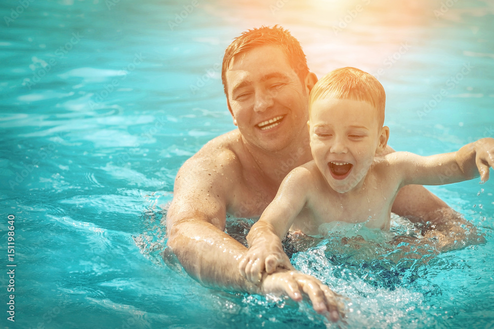 Father and son funny in water pool under sun light at summer da Father and son funny in water pool under sun light at summer da