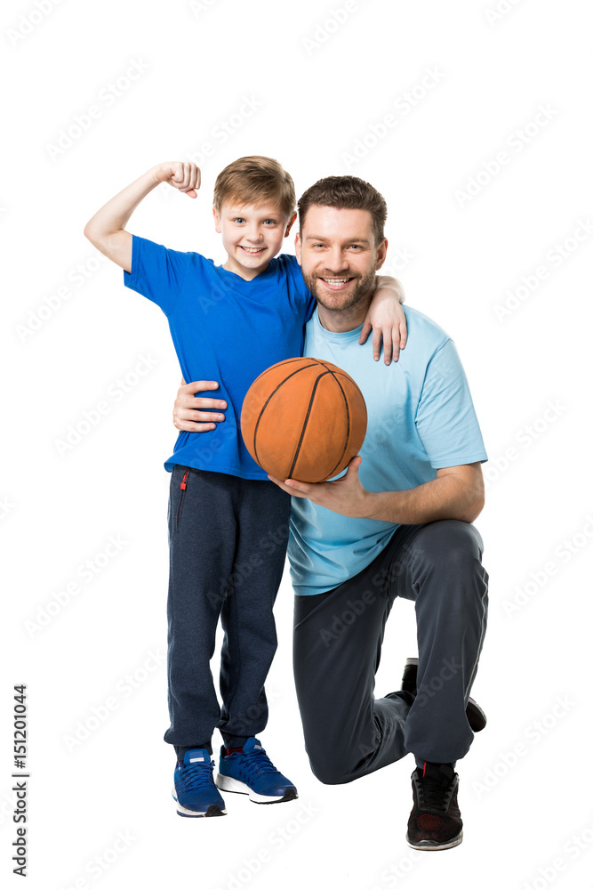 Smiling father and child ready to play basketball. Boy showing his biceps isolated on white