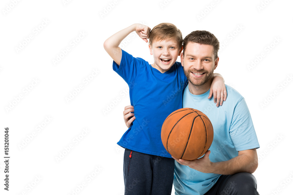 Smiling father and child ready to play basketball. Boy showing his biceps isolated on white Smiling father and child ready to play basketball. Boy showing his biceps isolated on white