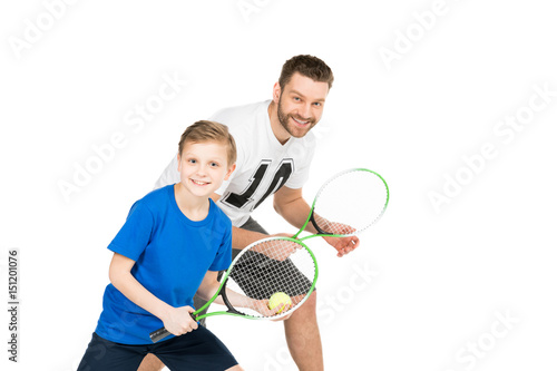 side view of active father and son with tennis racquets isolated on white